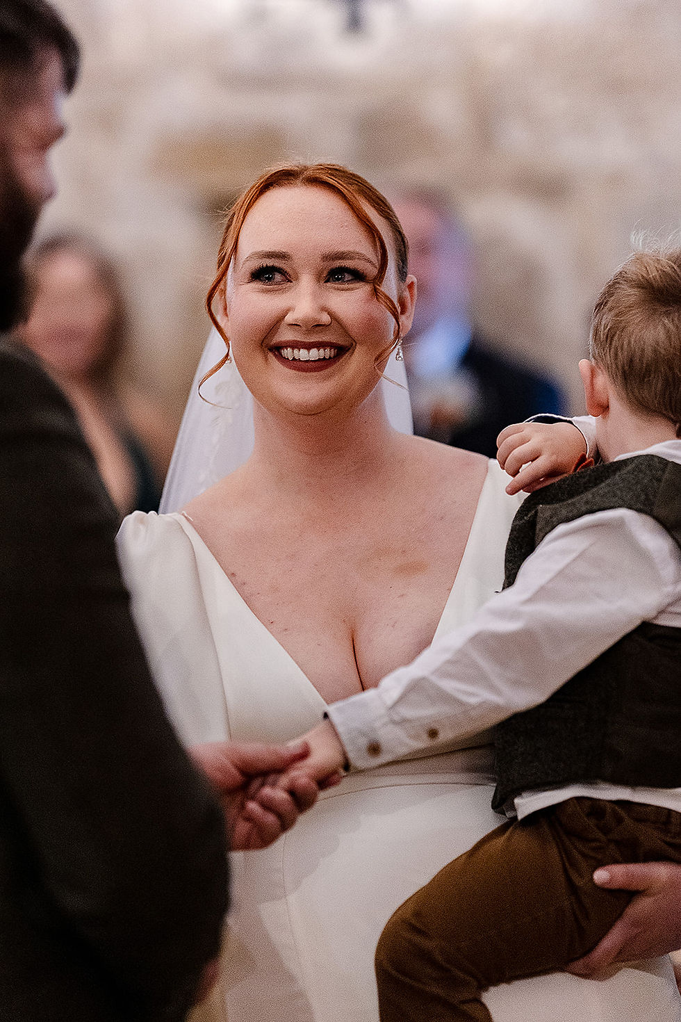 Bride holding Angus smiling towards her groom during their Danby Castle ceremony, smiling through the moment
