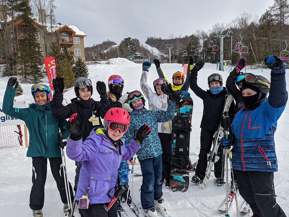 Kids skiing and snowboarding with hands in the air