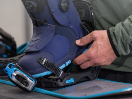 Snowboard boot being strapped into rentals binding