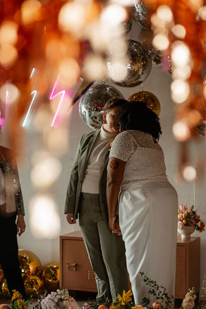 Queer couple celebrating with vibrant streamers - documentary-style LGBTQ+ wedding photography capturing candid joy