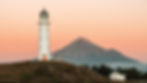 Lighthouse on a hill, mountain in background, sunset sky