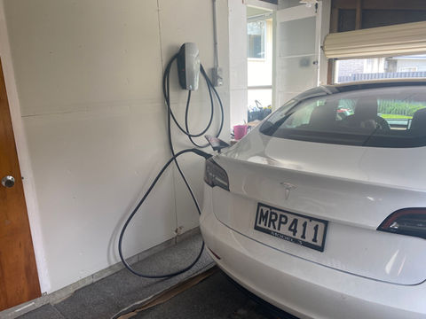 White car charging in garage with wall charger, plate MRP411