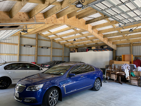 Blue car parked in a garage with high wooden ceiling