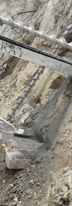 Construction worker shoveling concrete in a trench