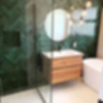 Modern bathroom with green herringbone tiles and wood vanity