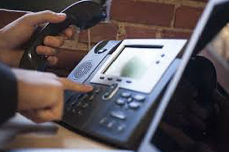 Person dialing a number on a DataTalk VoIP office phone.