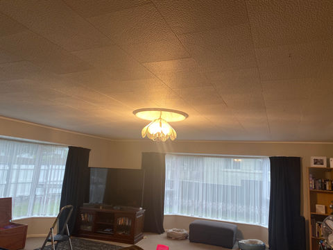 Warmly lit living room with ceiling light and curtained windows