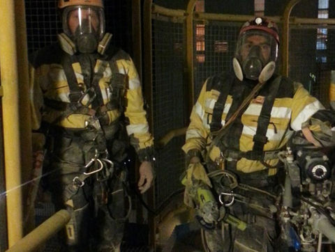 Two workers in protective suits, helmets, respirators, and harnesses