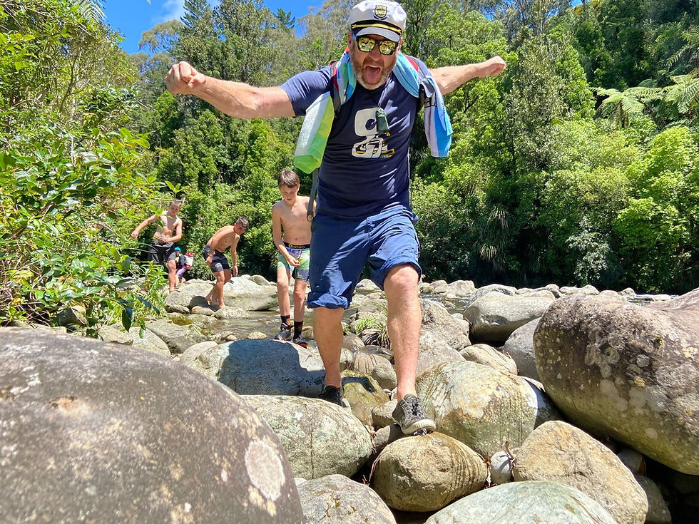 Man and boys balancing on rocks during a summer camp.