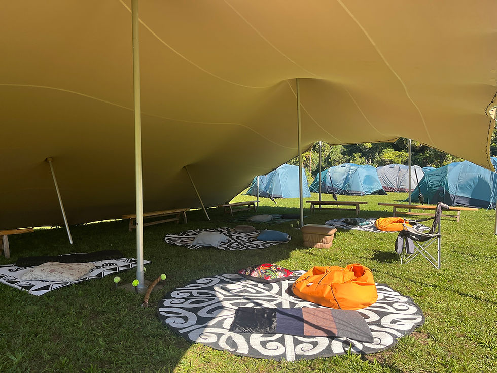 Outdoor campsite lounge under a tan stretch tent canopy