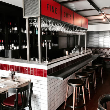 Restaurant bar with stools, red tile, and 'FINE' sign