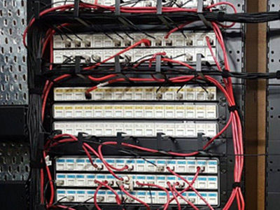 Network patch panels with organized red and black cabling.