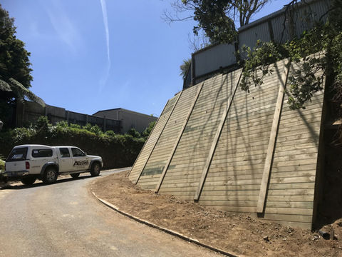 Wooden retaining wall along a curved road with a white truck