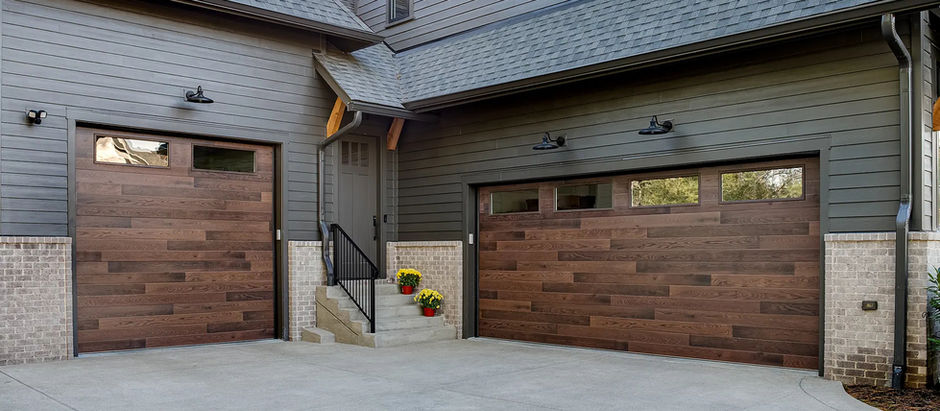 Eye level view of contemporary plank style garage doors with windows on the top section on the side of a suburban home.