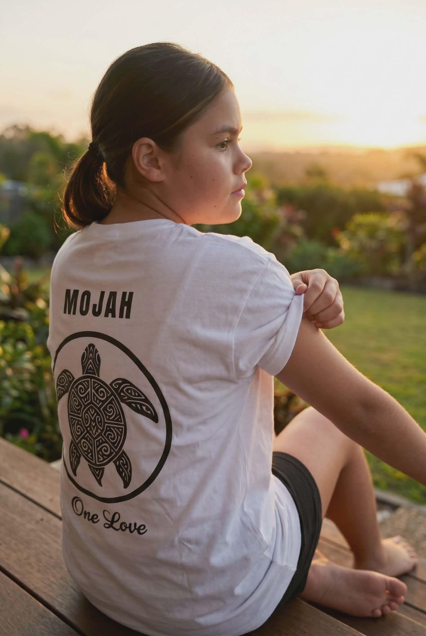 Girl wearing white MOJAH Honu (Turtle) Tee outdoors.
