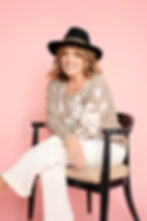 A lady on a pink backdrop wearing hat and showing her fun personality