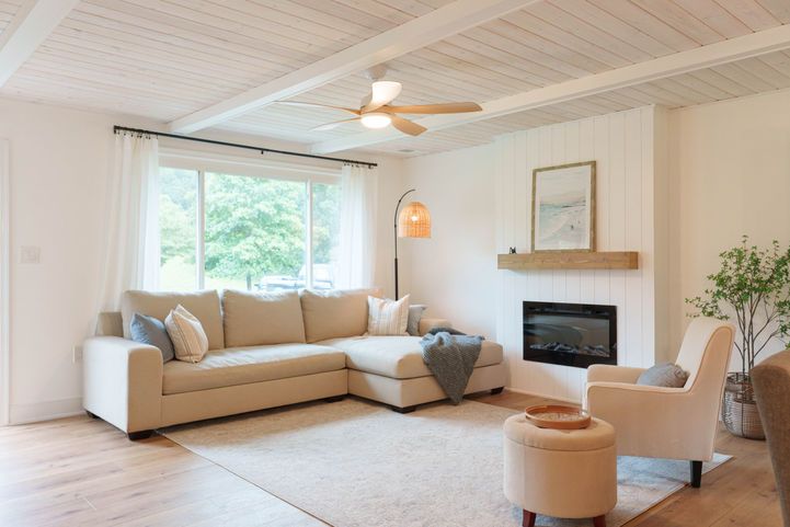 After renovation: cozy styled living room with white fireplace wall, decorative accents, and fresh natural light.
