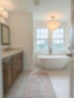 Bright luxury bathroom with freestanding tub, dark wood vanity, large window, and elegant chandelier – Luxury Bath project by Applewood Interiors.