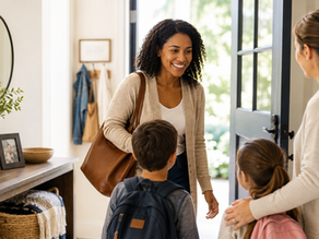 Professional nanny arriving at a family's home on her first day while parents and children warmly welcome her.