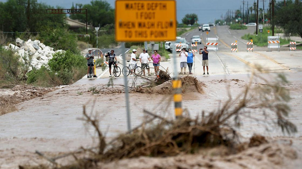 a flooded wash and pedestrian onlookers after a sever monsoon storm in southern Arizona