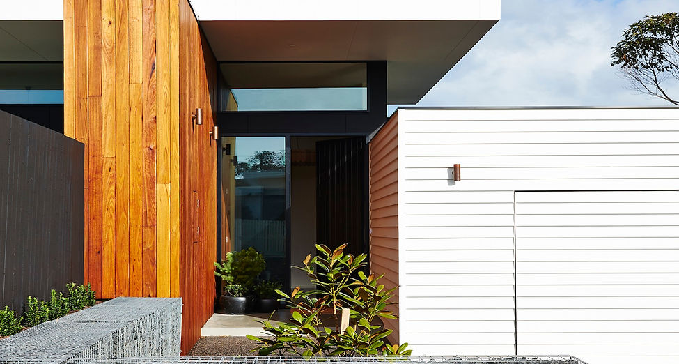 Contemporary Ocean Grove home exterior with timber and white cladding, gabion stone wall, and minimalist landscaping
