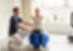 A physiotherapist helping his patient. An older lady sitting on a gym ball doing exercise