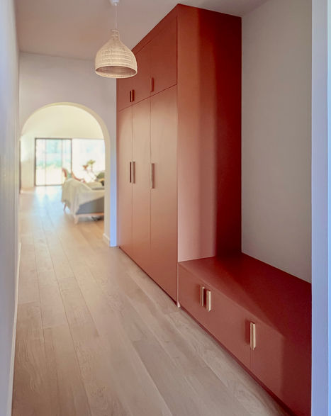 Un grand meuble sur mesure avec une 
partie vestiaire et une banquette terracotta
Les poignées arrondies rappellent le passage cintré vers le salon