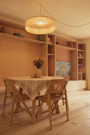 détail de la suspension parasol frangée en raphia, en rappel de la niche revêtue de raphia, et de la niche du meuble tv teintée en blush, comme les façades de cuisine
