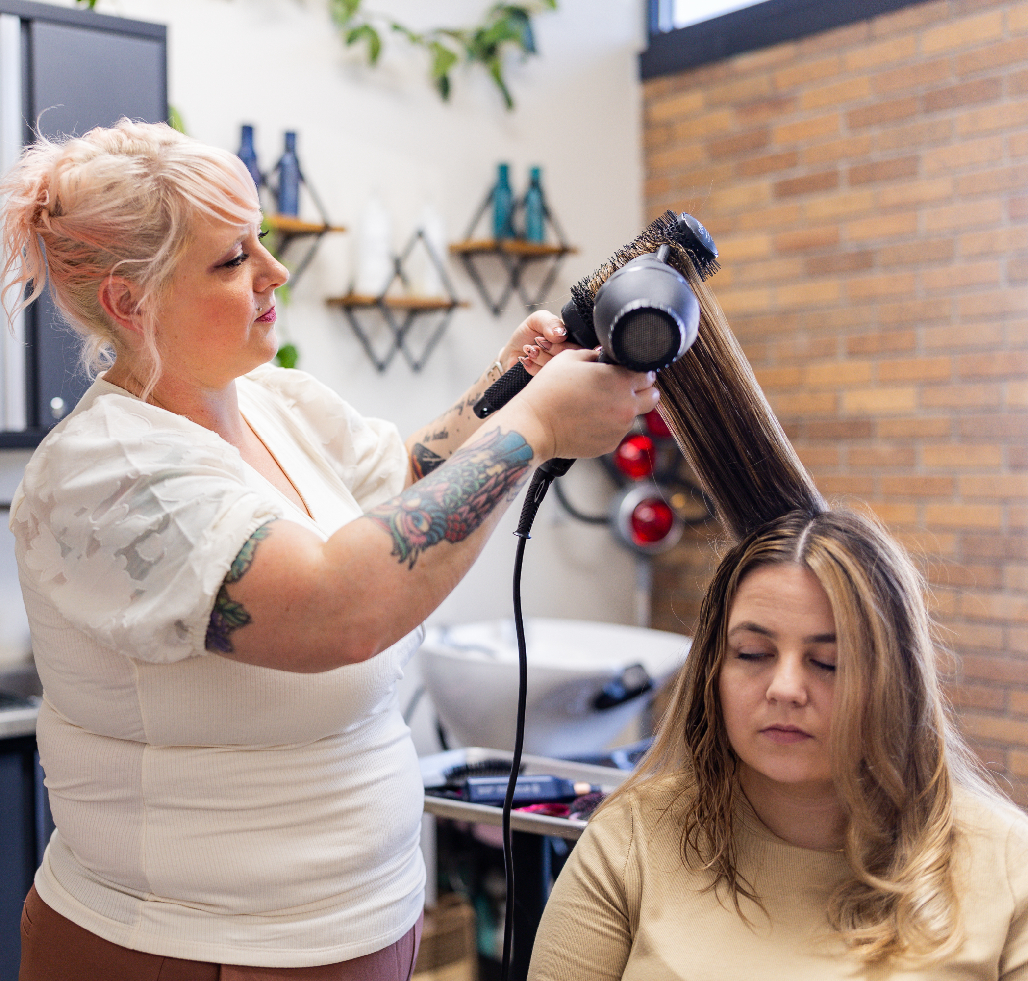 The owner of Flaired Beauty doing a round brush style on a client