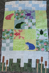 A baby quilt with frogs in blues and greens