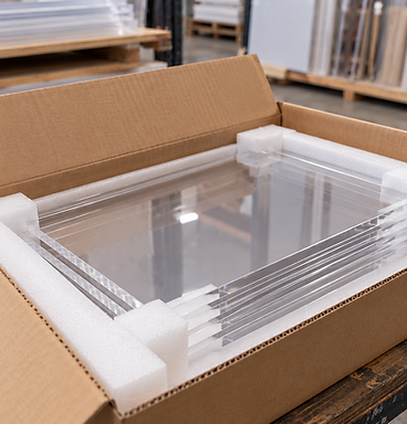 Clear acrylic sheets protected with foam packaging inside a cardboard shipping box