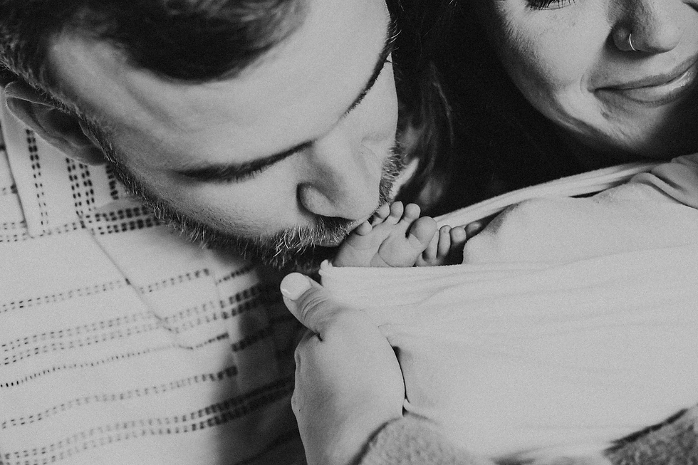 black and white photo of father kissing baby's feet