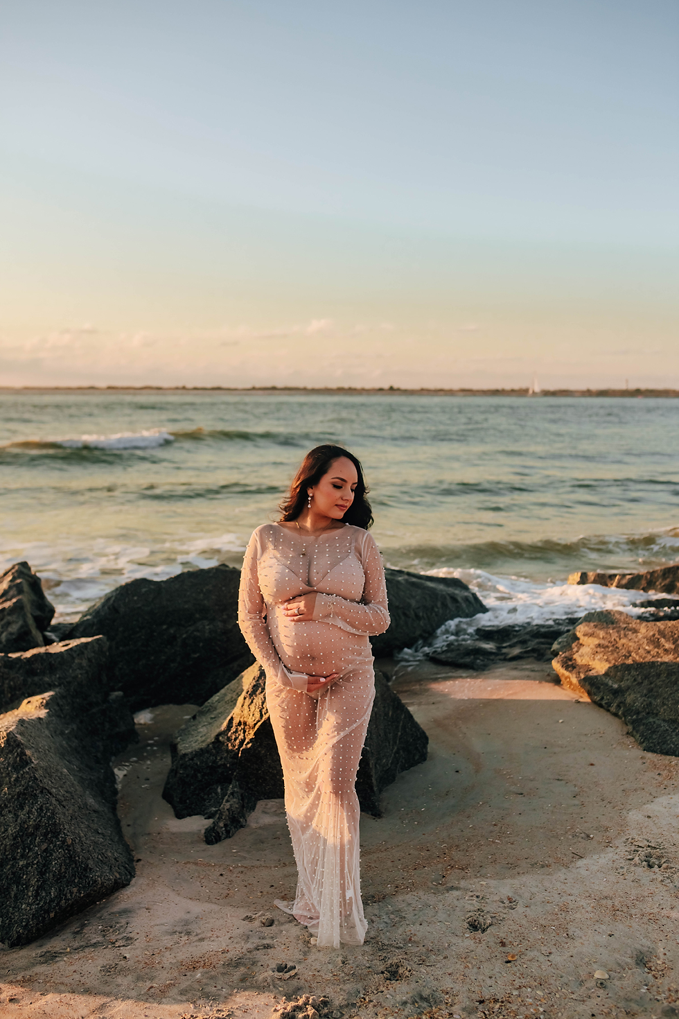 expectant mom posing on rocky beach during sunrise maternity portraits