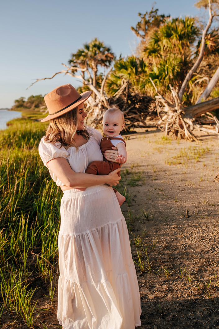 mother standing on riverbed holding baby boy