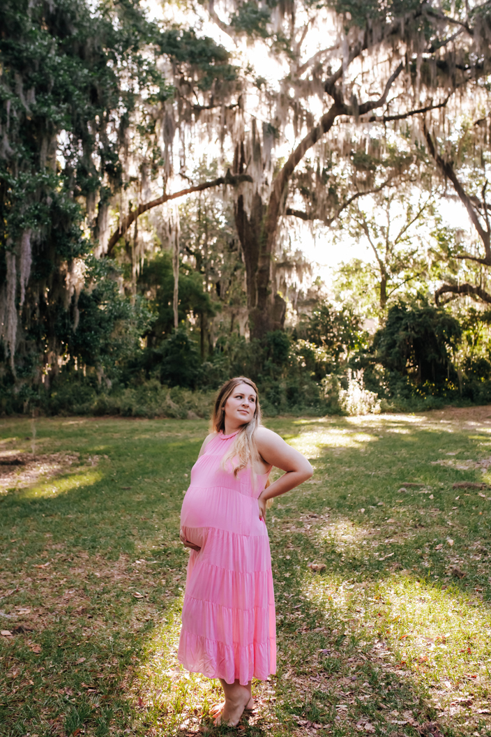 expecting mother in a pink dress poses for maternity photoshoot