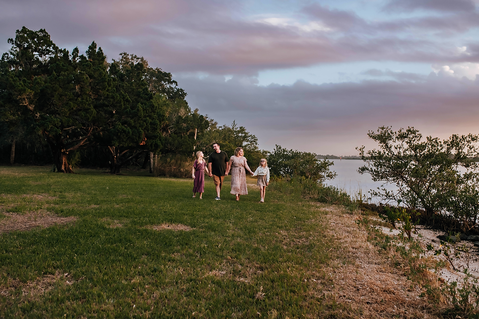 family walking hand in hand by river at sunset for family photos