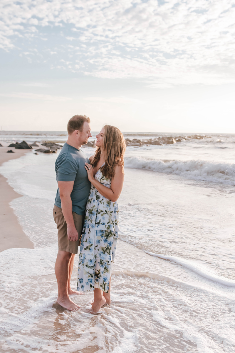 parents standing in the tide looking at each other during sunrise beach family photoshoot
