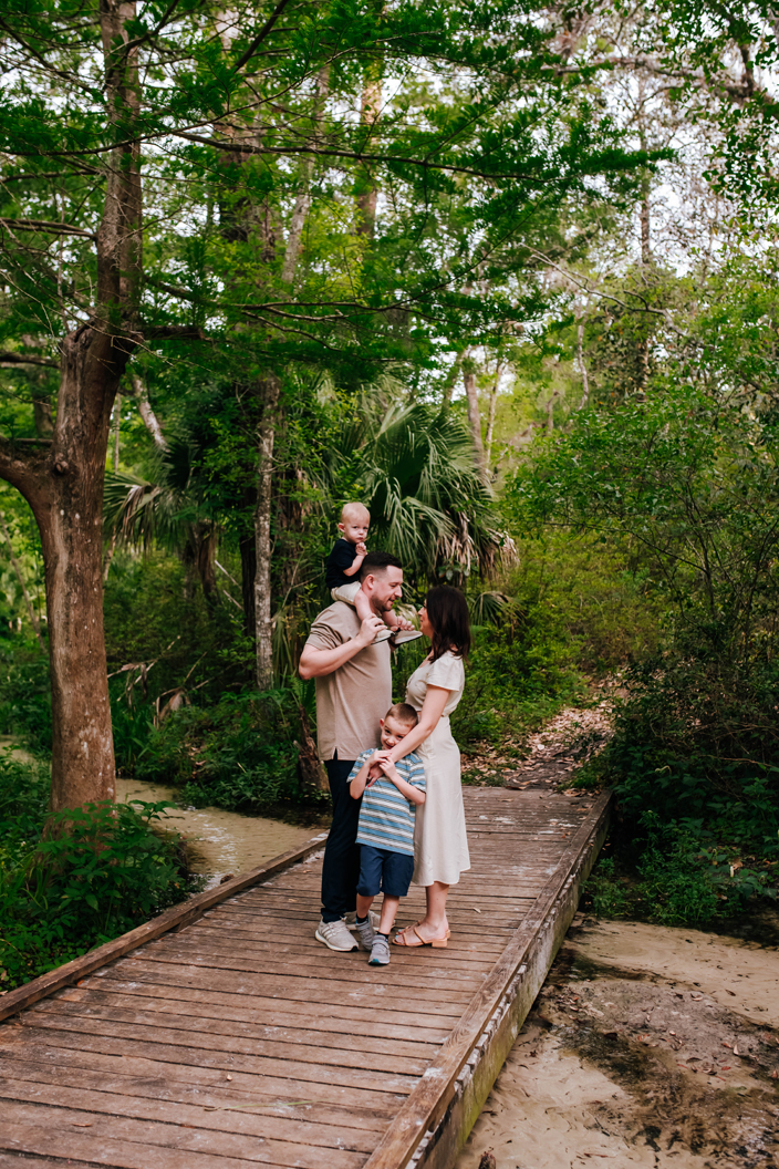 family together on wooden bridge over creek during state park family photoshoot