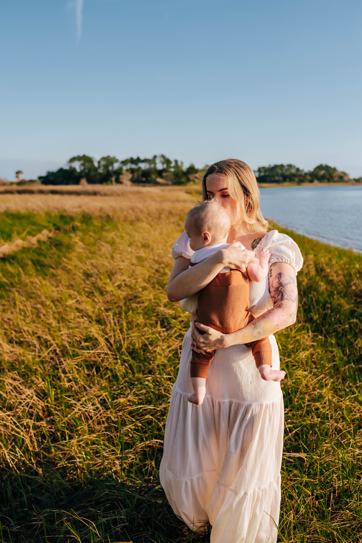 mom cuddling baby boy surrounded by salt marsh