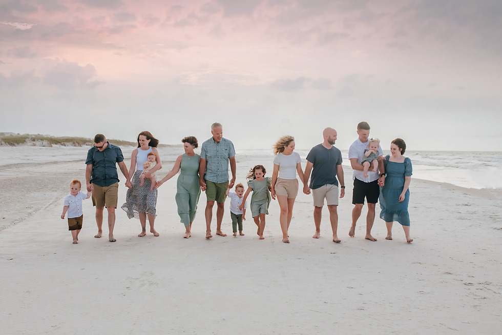 family of 13 walks together on the beach at sunset during family photoshoot