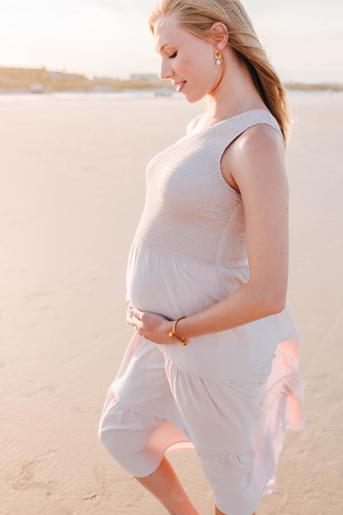 pregnant mother poses in the sunset light on the beach for maternity photoshoot