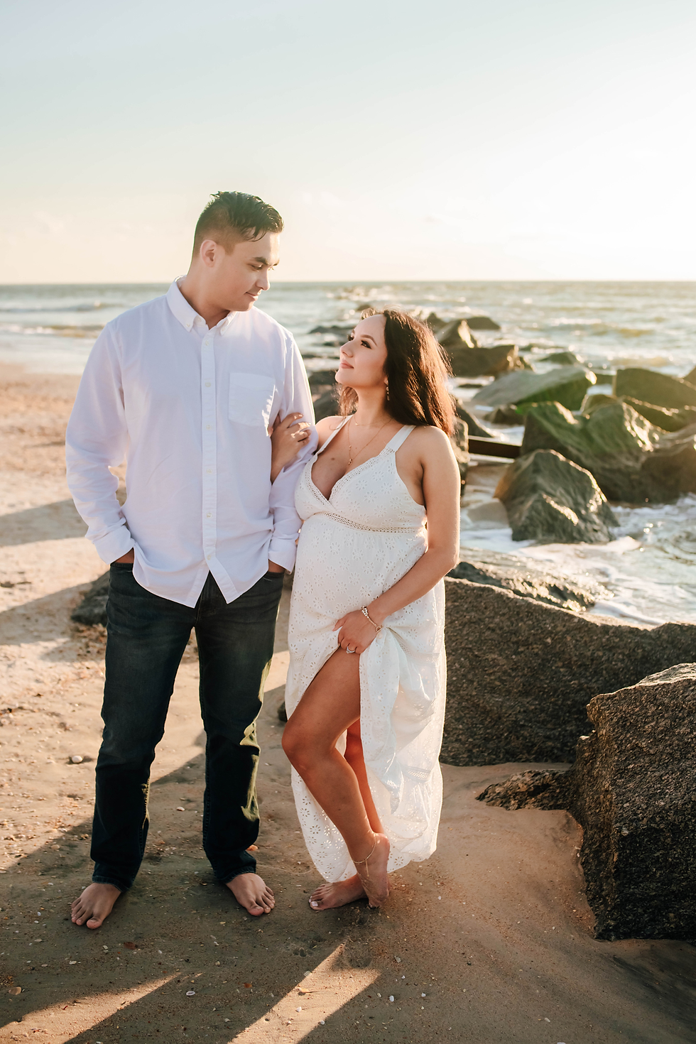couple looking at each other during sunrise beach maternity portraits
