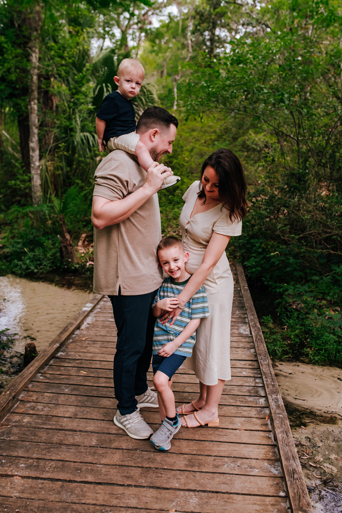 family cuddling together on wooden bridge during family portraits