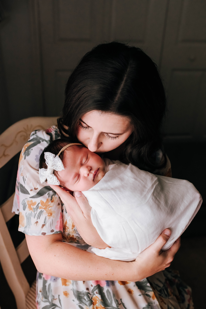 mom kissing newborn baby girl during newborn photoshoot