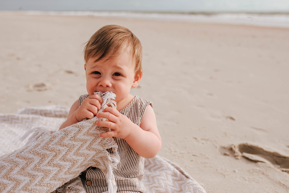 baby boy holding a blanket to his mouth during his beach family portrait session