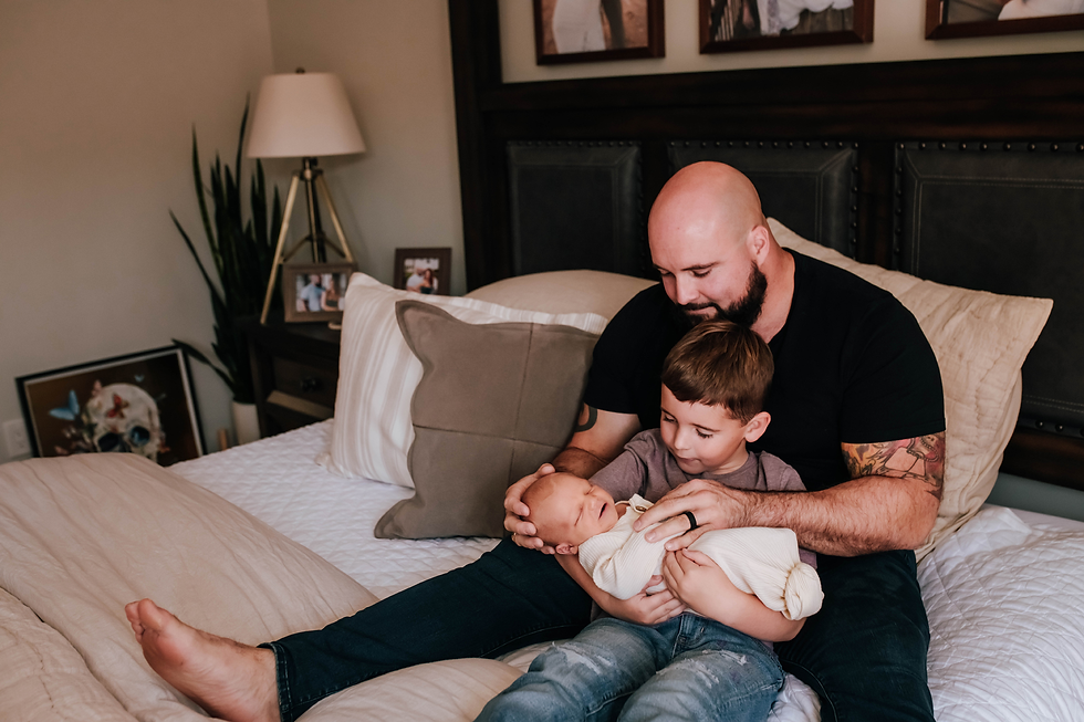 father helping older son hold newborn baby