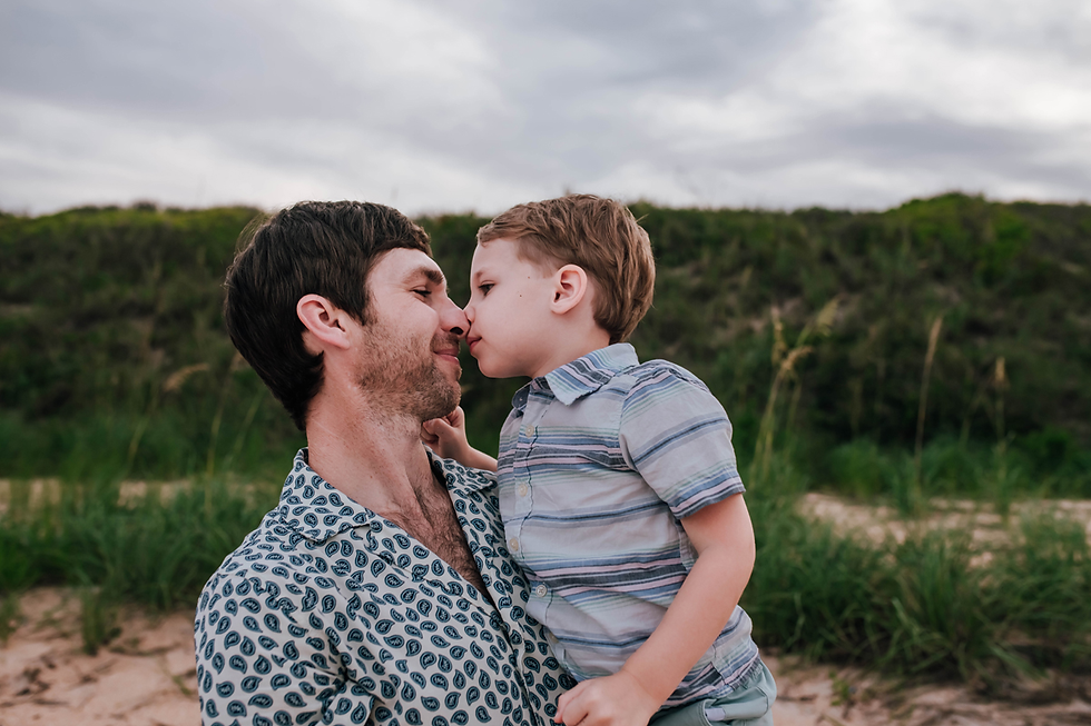 father and son nose to nose in front of grassy dunes during beach family photography session