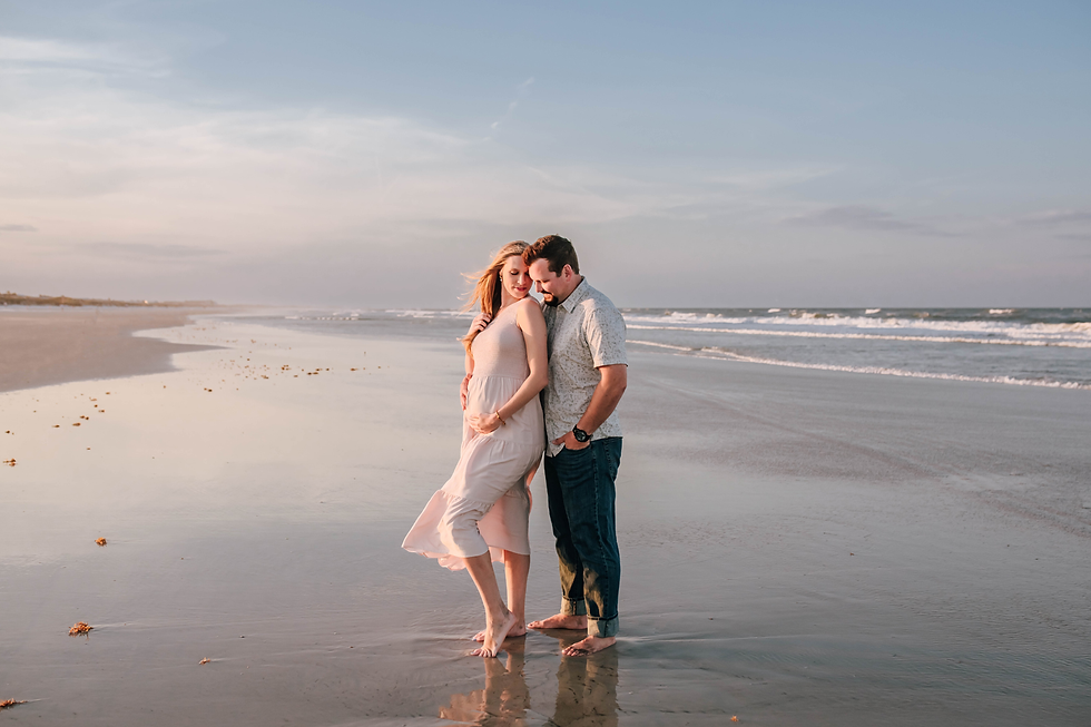 expecting couple stands in the tide as they cuddle together during beach maternity portrait session