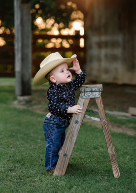 cowboy posing in cowboy outfit with hat for his first birthday session at AW Perry Museum for his milestone session with jc photography and design a mckinney family photographer 