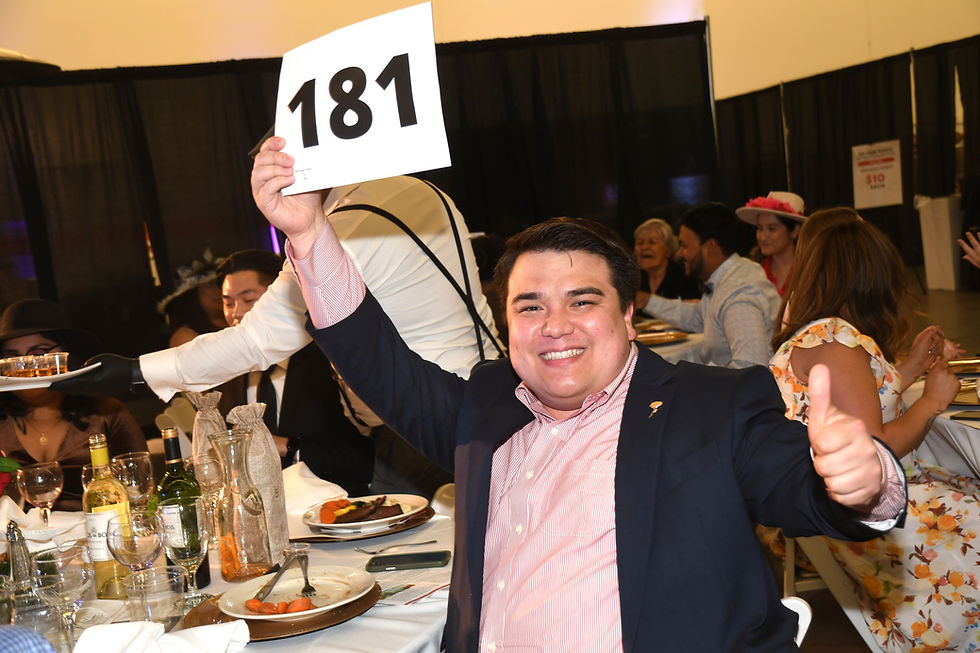 Auction participant raising his paddle to bid on an item at FARSB's Million Meals Gala Run for the Roses event.